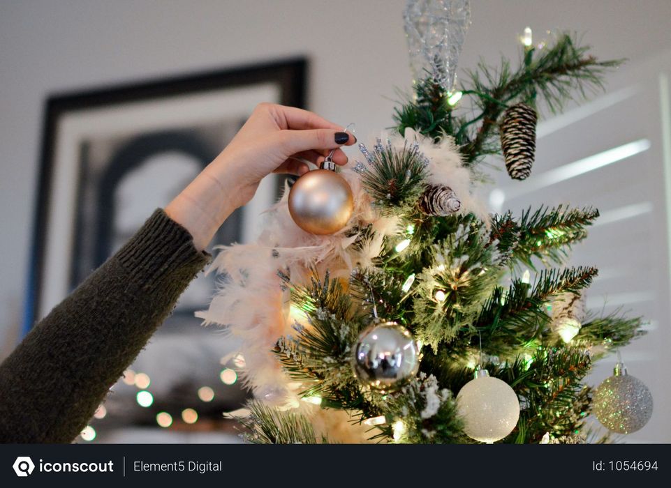 Person Hanging Golden Bauble To Christmas Tree Photo