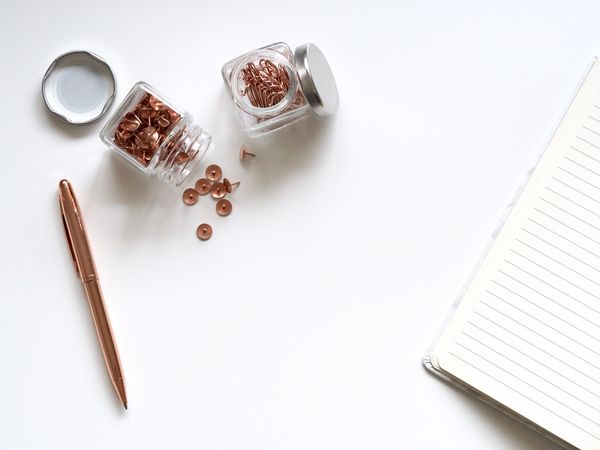 Bunch Of Thumbtacks With Two Clear Glass Containers On White Surface Photo