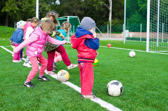 Children's Kicking Football In Garden Photo