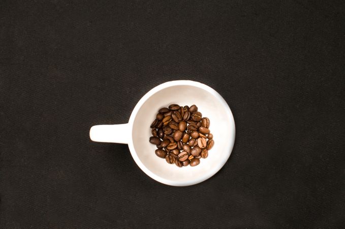 Coffee Beans In White Ceramic Cup On Black Table Photo
