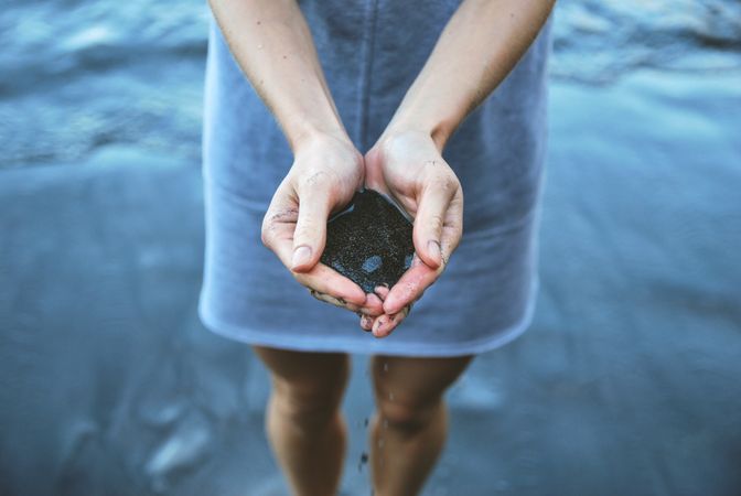 Girl Hold Some Water And Black Sand In Hand Photo