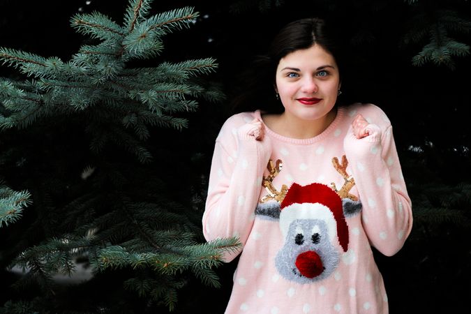 Girl Wearing Christmas Reindeer Printed Top Standing Near Pine Tree Photo