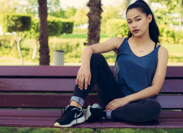Girl Wearing Racerback Top Sitting On Bench In Park Photo