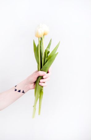 Girl With Tattoo On Hand Holding Beige Flowers Photo
