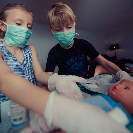 Kids Playing Surgeon With Doll Photo
