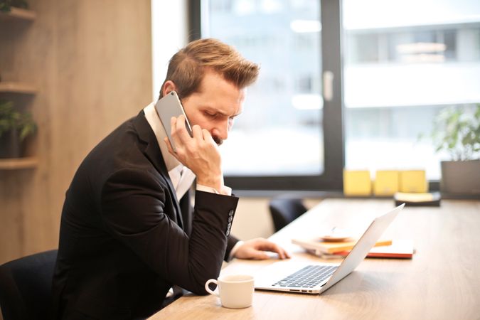 Man Having A Phone Call In-front Of A Laptop Photo