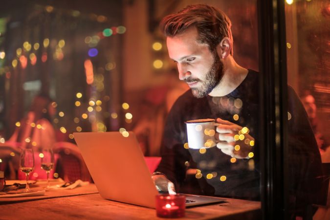 Man Holding Mug In Front Of Laptop Photo