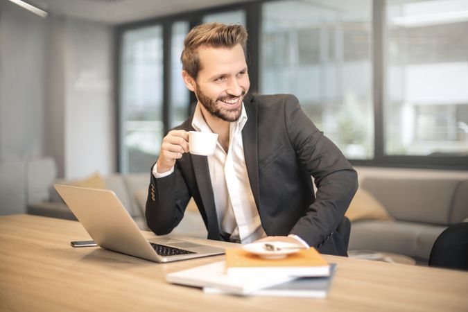 Man Holding White Teacup In Front Of Gray Laptop Photo