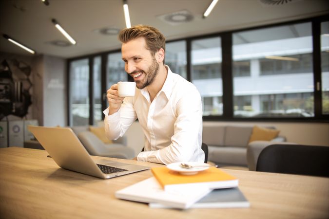 Man Sitting On Chair While Holding Cup In Front Of Table Photo
