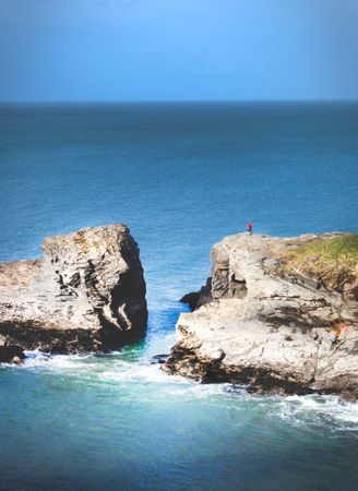 Man Standing Near Cliff Surrounded By Body Of Water Photo