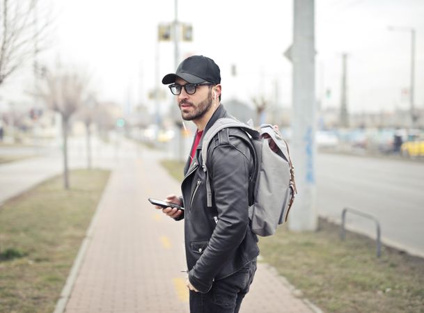 Man Wearing Black Leather Jacket Holding Smartphone Photo