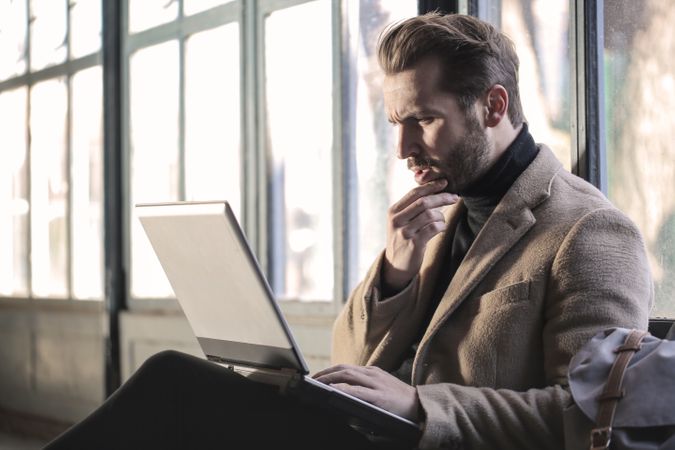 Man Wearing Brown Jacket And Using Grey Laptop Photo