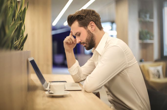 Man With Hand On Temple Looking At Laptop Photo