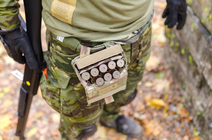 Person In Green Camouflage Print Pants Carrying Shotgun Shells Photo
