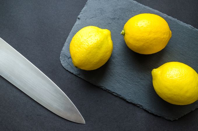 Three Lemons On Chopping Board Near Knife Photo