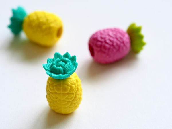 Three Pineapple Figures Erasers On White Surface Photo