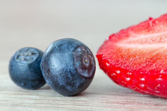 Two Blueberries With Half Strawberry On Wooden Table Photo