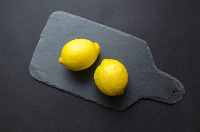 Two Lemons On Black Wooden Board Photo