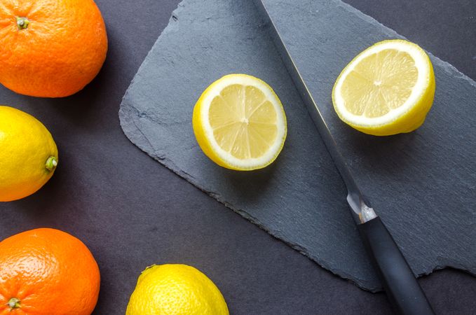 Two Orange And Three Lemons On Gray Surface With Knife Photo