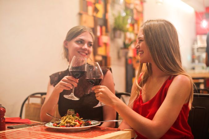 Two Women Holding Long-stem Wine Glasses With Red Liquid Photo