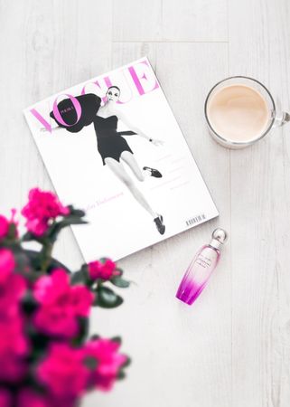 Vogue Magazine Beside Perfume Bottle And Coffee Cup On Wooden Surface Photo