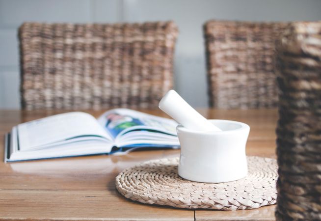 White Ceramic Mortar And Pestle Beside Book On Wooden Table Photo