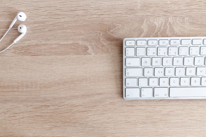 White Earphone And Keyboard On Wooden Table Photo