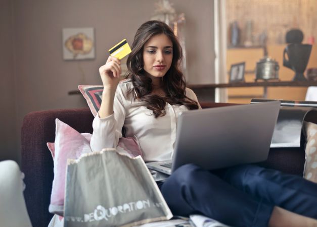 Woman Holding Card While Operating Silver Laptop Photo