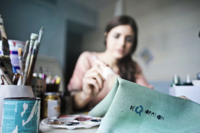 Woman Holding Paper Near Paint Brushes Photo