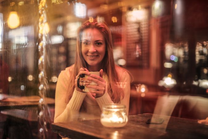 Woman Holding White Ceramic Cup Sitting Near Brown Wooden Table Photo