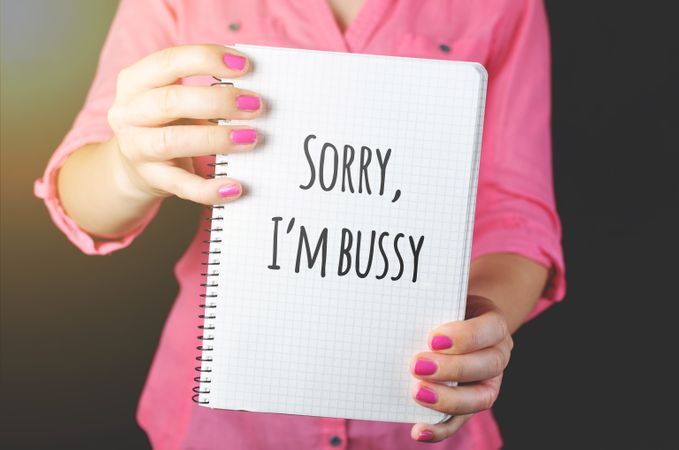 Woman In Pink Long-sleeved Shirt Holding White Book With Sorry, I'm Bussy Text Photo