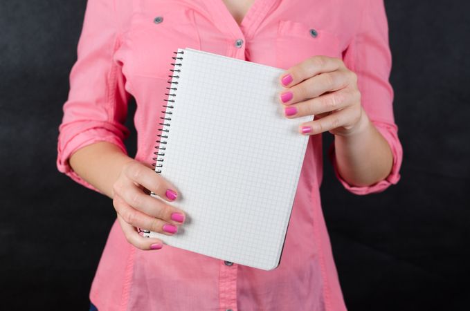 Woman In Pink Shirt Holding Grid Notebook In Her Hand Photo