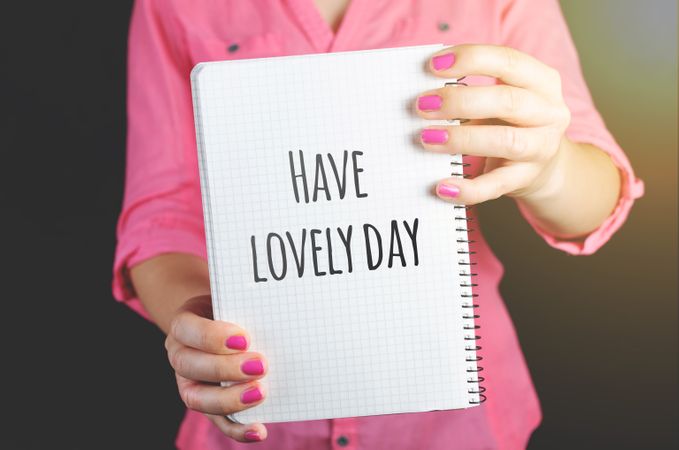 Woman Wearing Pink Dress Holding Graphing Notebook With Have A Lovely Day Text Photo