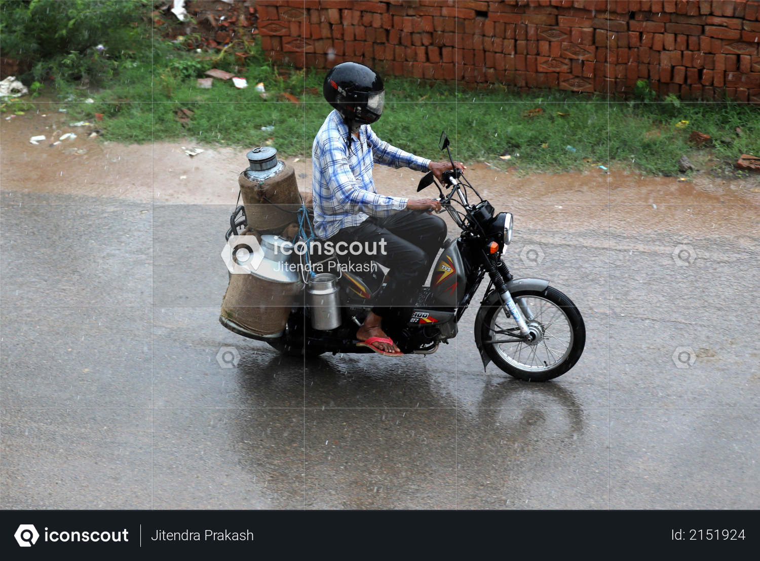A milkman is riding his motorcycle with milk cans in heavy rain - Monsoon Photo