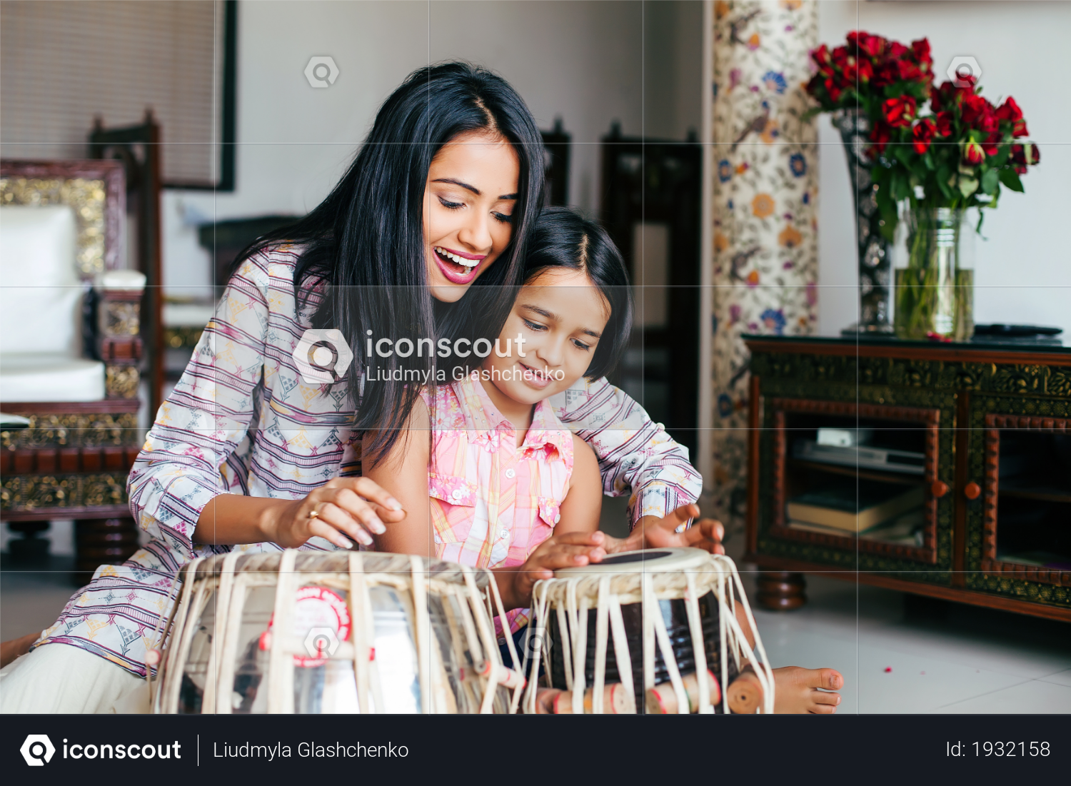Beautiful Indian woman wearing traditional kurta teaching her daughter to play Tabla Photo