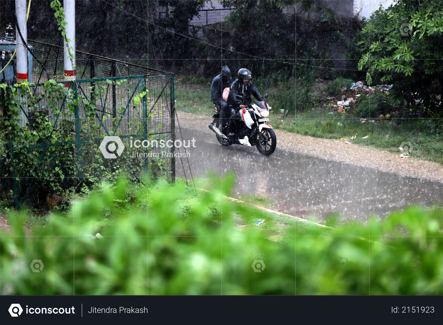 Indian Man in black raincoat & driving bike in rainy day, monsoon Photo
