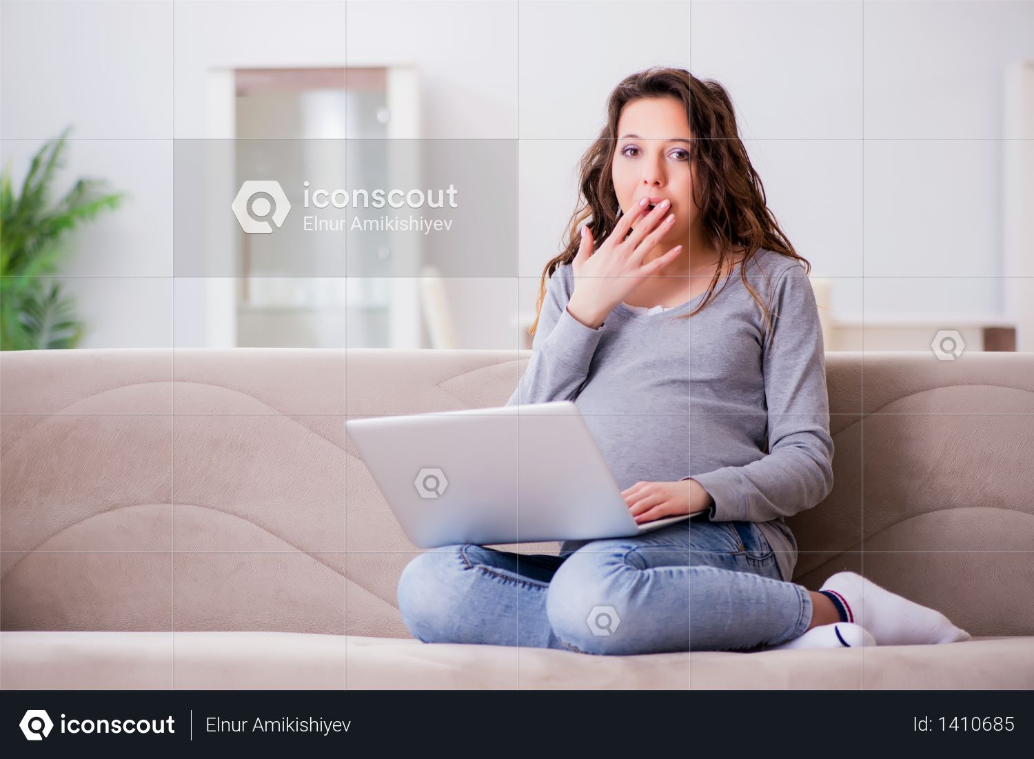 Pregnant woman working on laptop sitting on sofa Photo