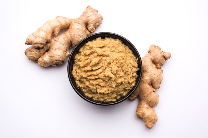 Premium Fresh mashed Ginger or Adrak paste in white bowl with raw ginger  over white background Photo download in PNG & JPG format
