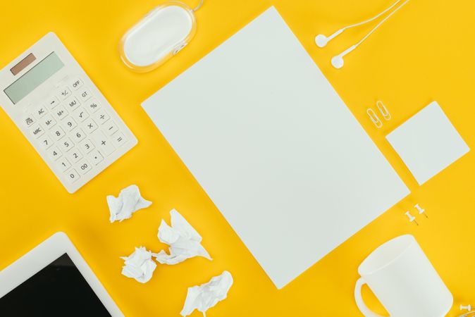 Top View Of Blank Sheet Of Paper, Crumpled Papers, Notes, Calculator, Earphones, Computer Mouse And Digital Tablet Isolated On Yellow Photo