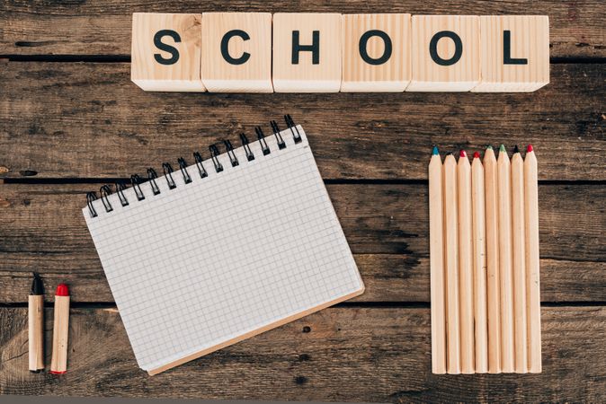 Top View Of Composition Of Colorful Pencils With Blank Notebook And Word School On Wooden Background Photo