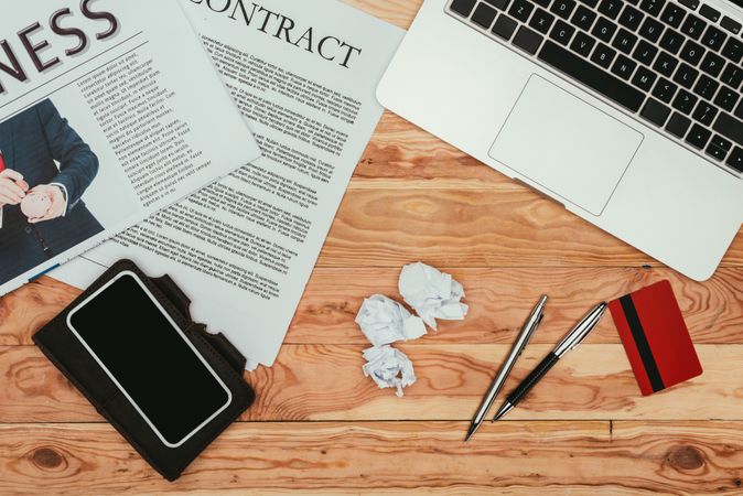 Top View Of Smartphone With Blank Screen, Contract Newspaper, Laptop And Credit Card On Wooden Table Photo